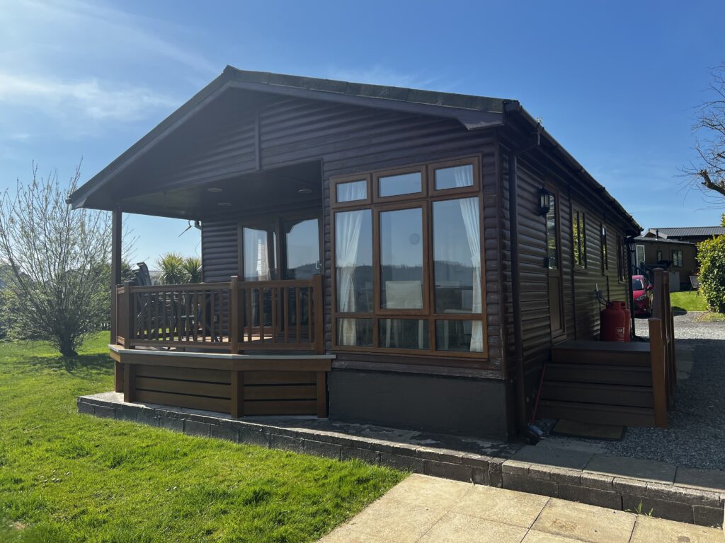 Luxury Holiday Lodge 3 a lodge with a porch and a lawn